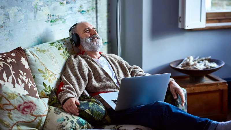 Older man relaxing on couch with headphones