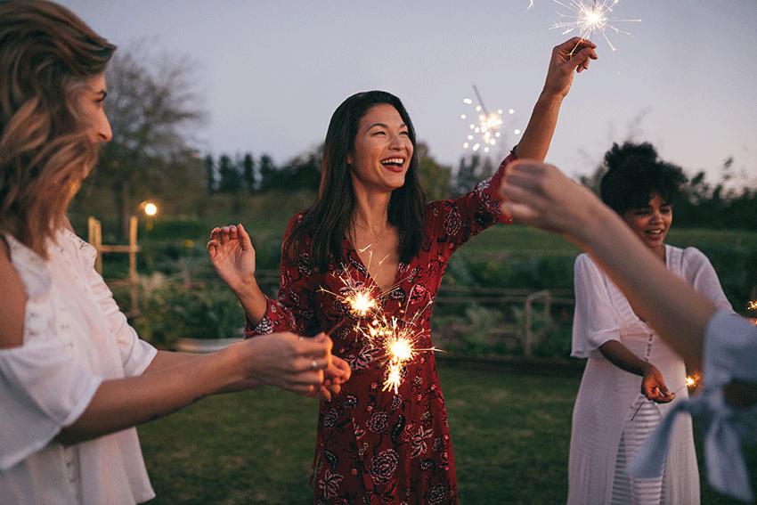 happy friends playing with sparklers outdoors